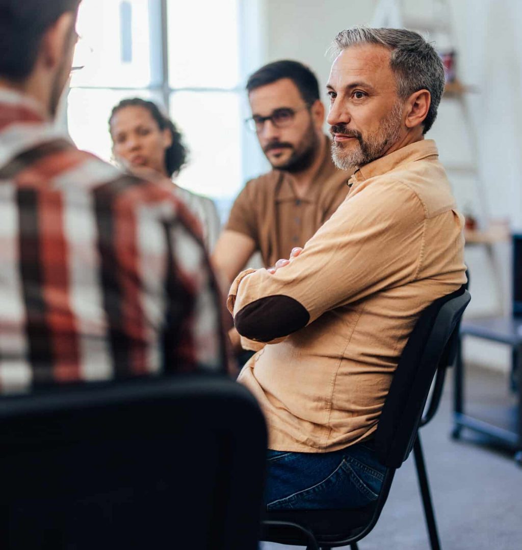 Serious-looking people carefully listen to their psychologist during the therapy.